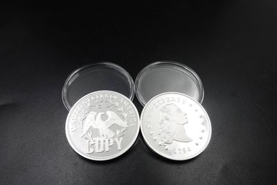 Two silver-tone replica-style pieces in clear capsules, one with a Liberty-style portrait and the other visibly stamped COPY