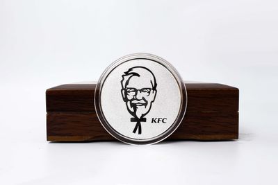 Silver-tone round coin with a prominent line-art chef portrait and black logo markings