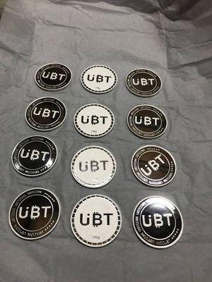Twelve round black-and-silver lettermark coins arranged in four rows with contrasting face finishes