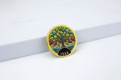 Round gold-rimmed coin with a detailed branching tree, multicolored foliage and small YEAR wording