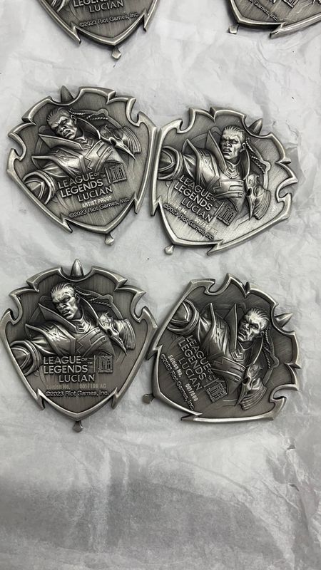 Four antique silver-look shield emblems showing raised fantasy characters and ornate pointed outlines on white fabric