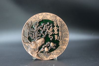 Large copper-tone coin showing an ancient branching tree over rocks, a green recessed field and Chinese calligraphy