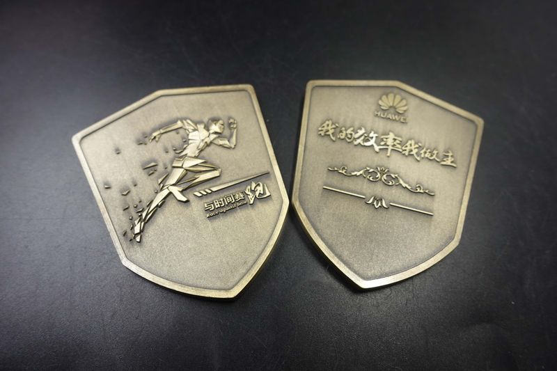 Two sides of antique silver shield badge with raised running figure and Chinese text