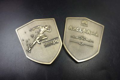 Two sides of antique silver shield badge with raised running figure and Chinese text
