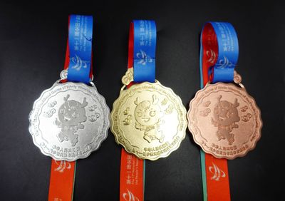 Three scalloped ribbon medals with cartoon mascot relief in silver gold and bronze tones