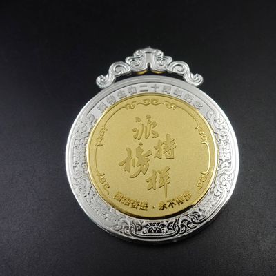 Round gold and silver tone award medal with ornate silver edge and curved top hanger