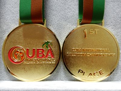 Gold-tone first-place ballroom dance medal with red logo accents and green brown ribbon