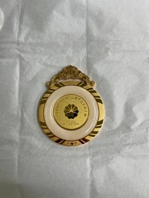 Gold-tone round medal with ornate crest hanger black center and striped border