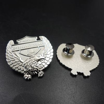 Front and back of silver eagle crest badge with feathered wings banner and two metal attachment posts