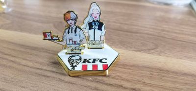 Freestanding metal restaurant staff recognition emblem with two illustrated figures and KFC logo on the base