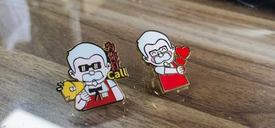 Two cartoon restaurant mascot lapel pins in white red and black showing food item and a red heart