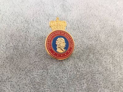Red blue and gold oval commemorative lapel pin with raised crown and central profile portrait