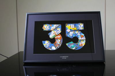 Dark presentation frame holding colorful number 35 anniversary metal artwork