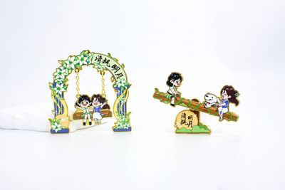 Two colorful childhood play scene souvenirs showing children and floral arch swing
