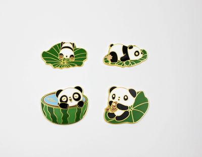 Set of four panda souvenir magnets with different poses in green leaves