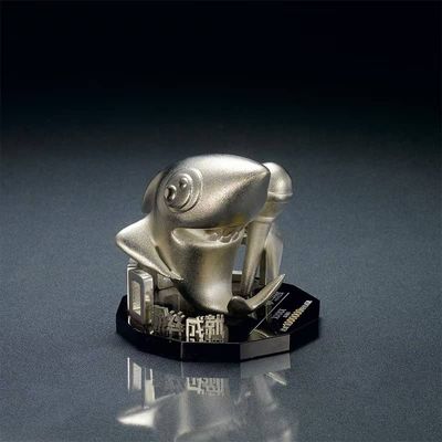 Silver-tone stylized cartoon figure leaning over geometric symbols on a small black trophy base