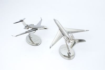 Two silver-tone airplane miniatures on separate circular desk stands with tilted mounting rods